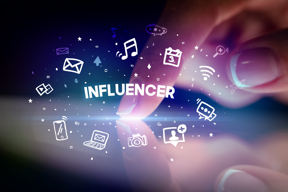 Finger touching tablet with drawn social media icons and INFLUENCER inscription, social networking concept